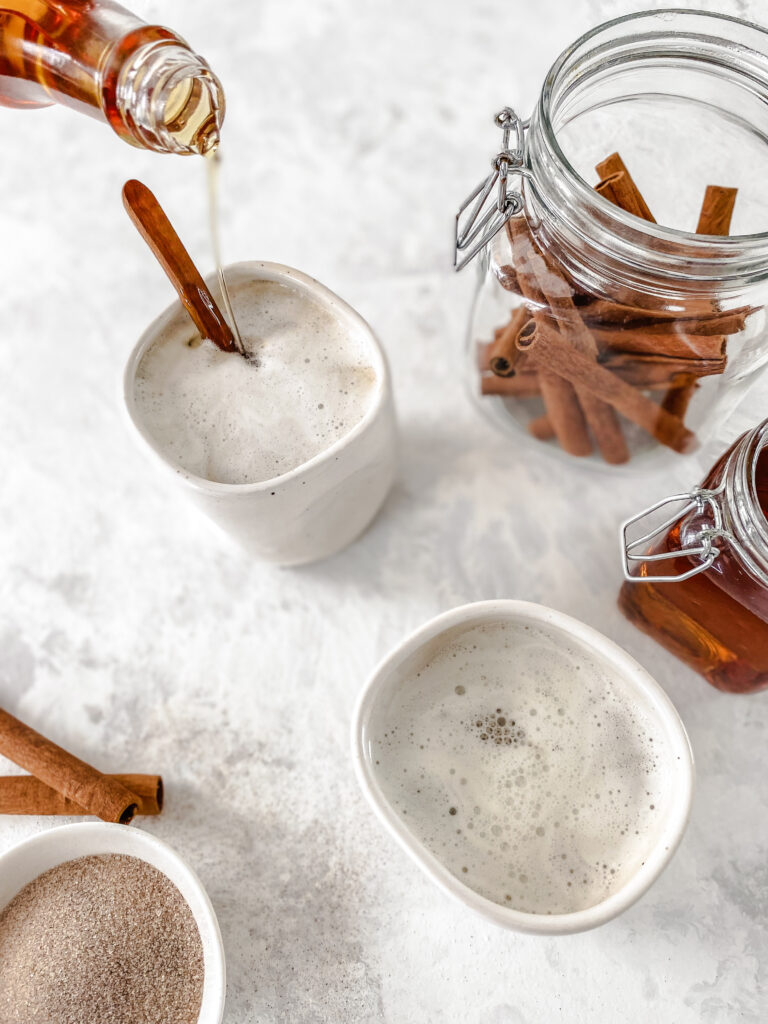 Copycat Cinnamon Dolce Syrup being poured into a mug of steamed milk.