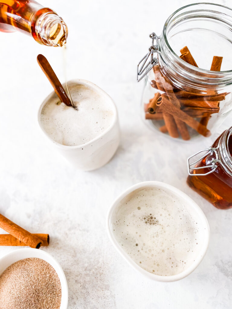 Copycat Cinnamon Dolce Syrup being poured into a mug of steamed milk.