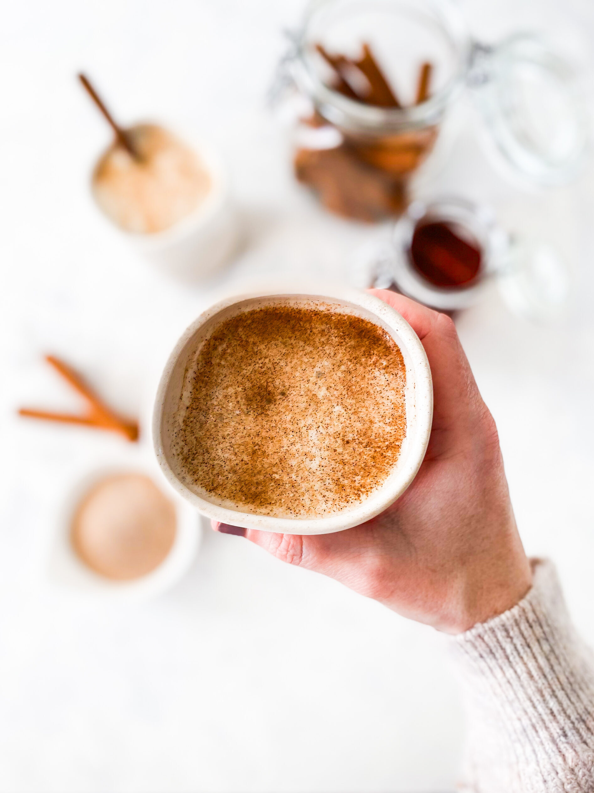 A hand holding a mug of Copycat Starbucks Cinnamon Dolce steamer.