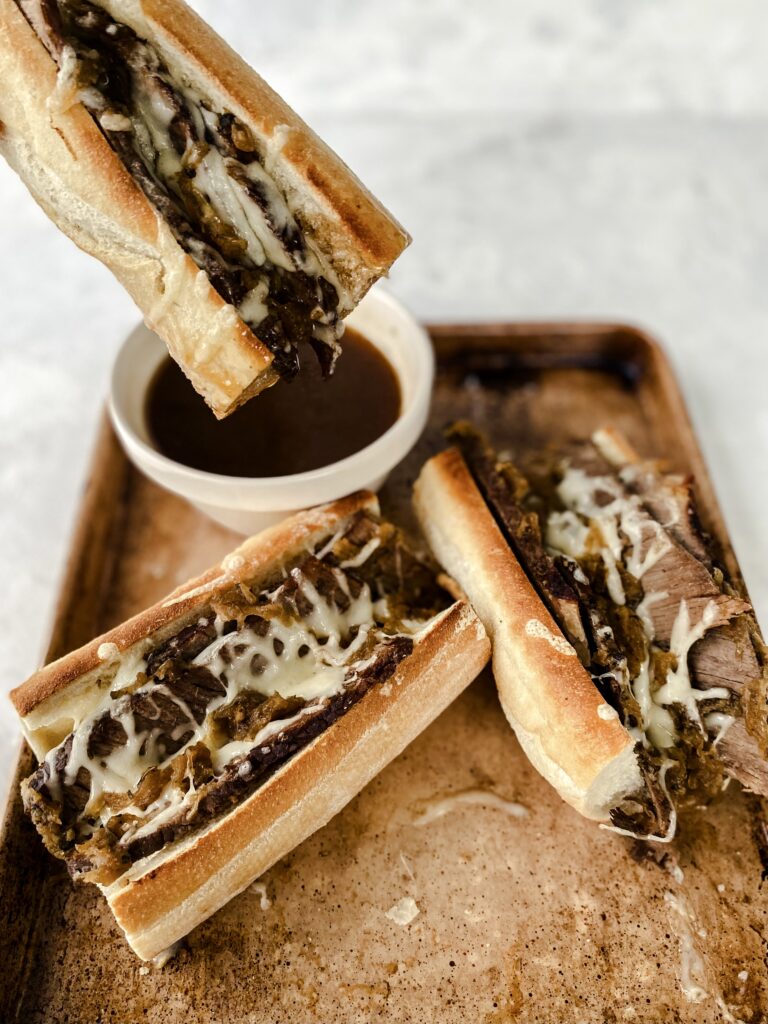 A French dip sandwich being dipped in jus.