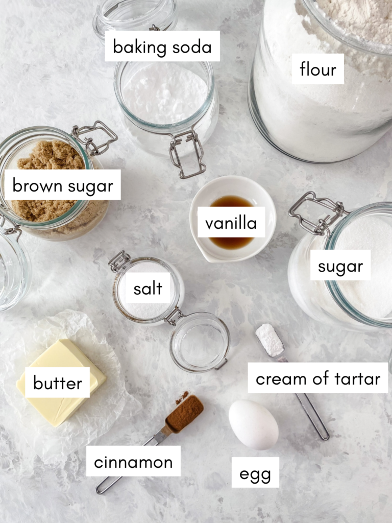 All the ingredients needed for Cinnamon Snickerdoodle cookies set out on a marble counter.