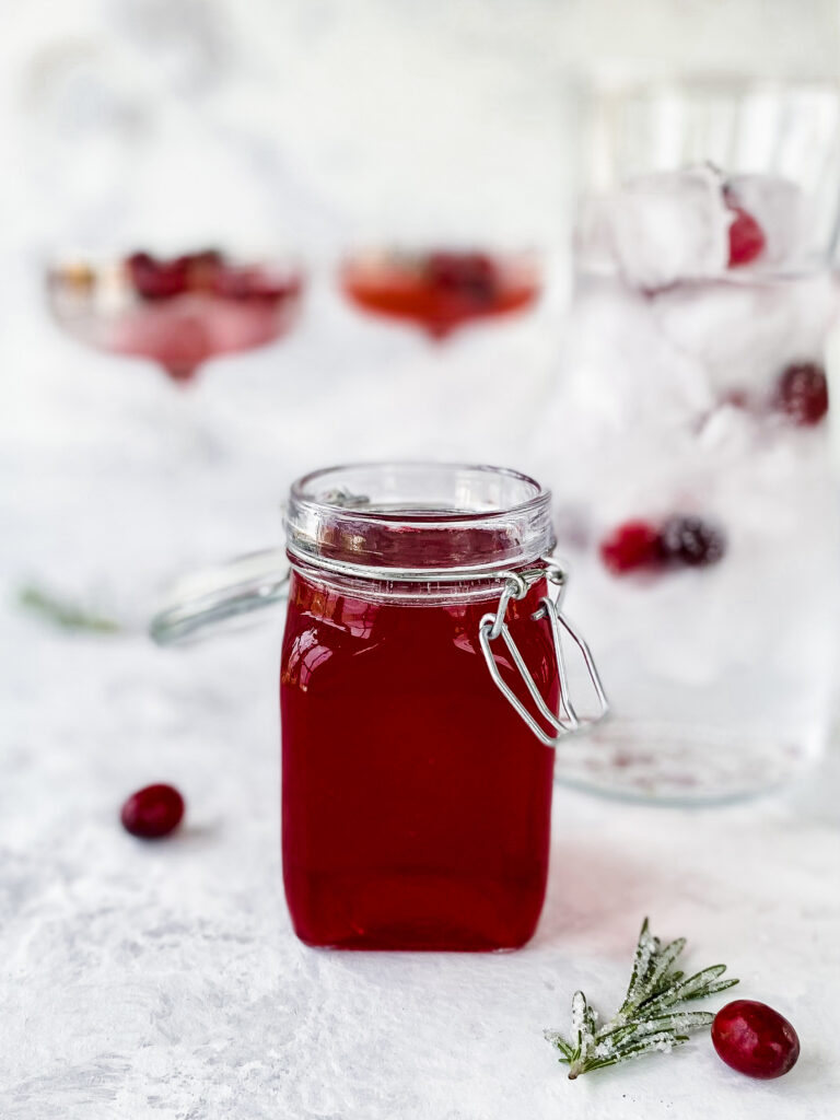 A glass jar of cranberry rosemary shrub.