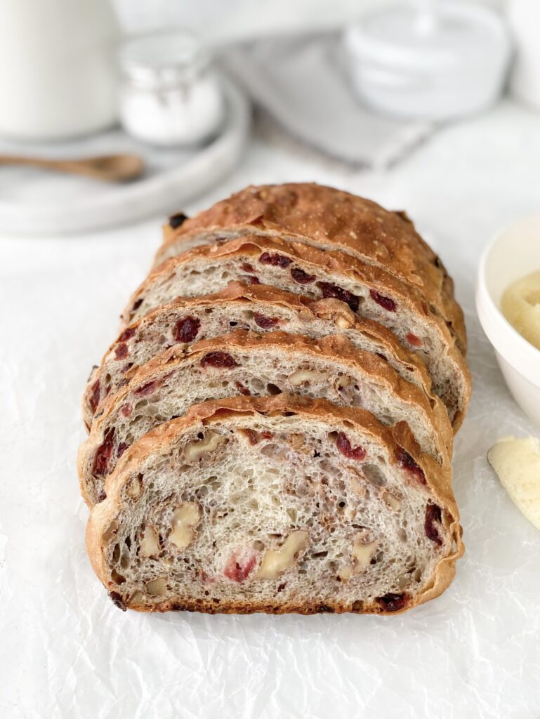 Homemade cranberry walnut bread, sliced next to a knife with butter.