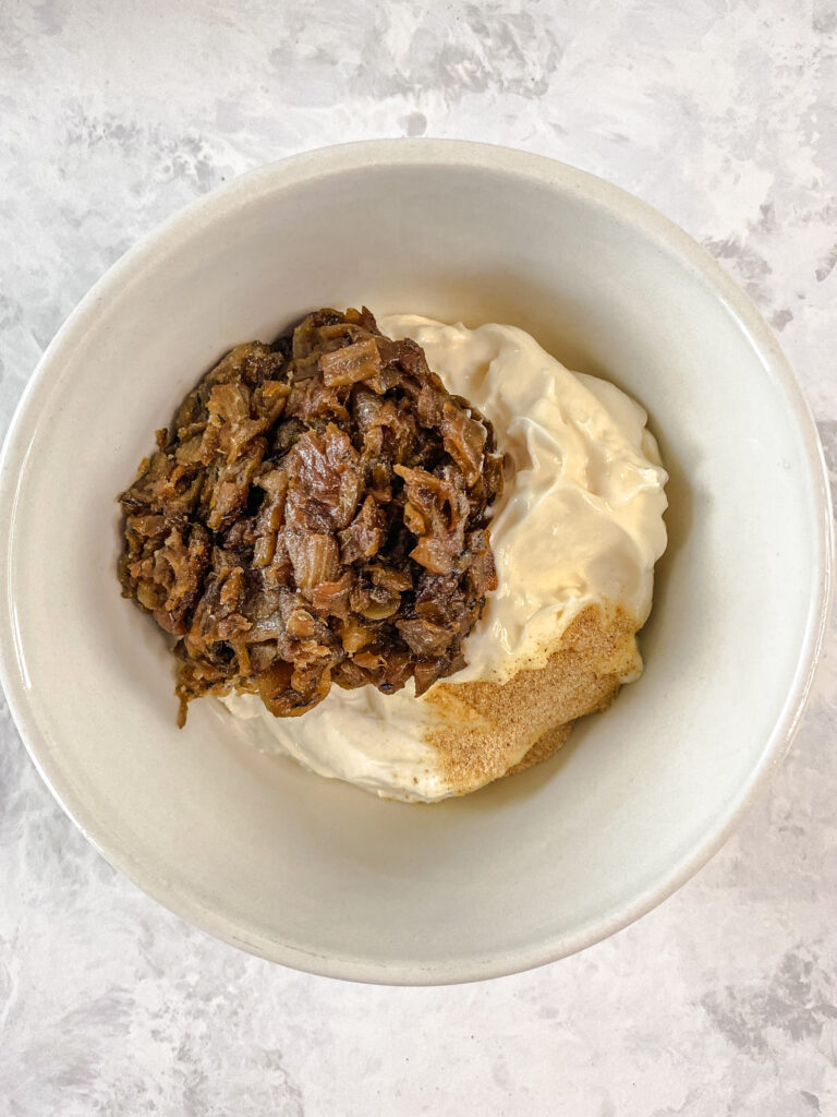 Caramelized onions, Greek yogurt, mayonnaise, and garlic powder in a bowl.