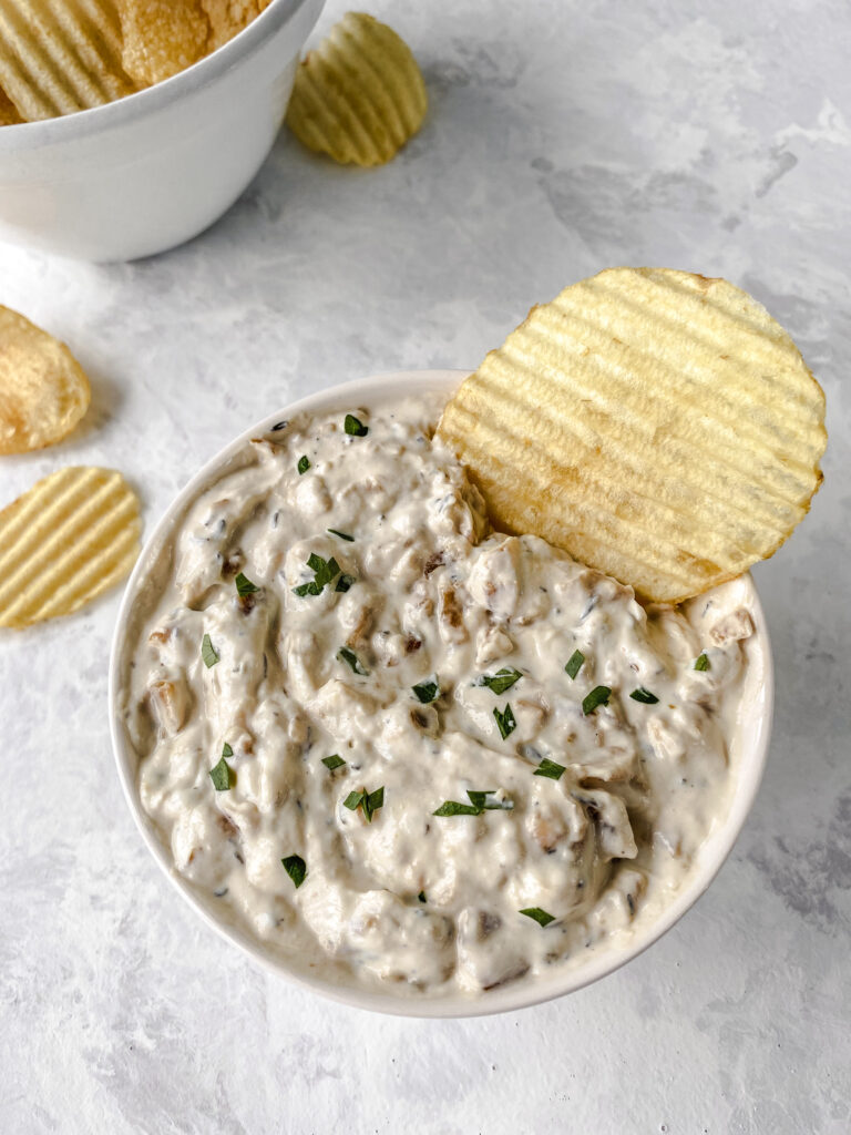 A ripple chip in a bowl of caramelized onion dip.