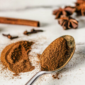 A spoonful of Homemade Baking Spice Blend next to a cinnamon stick and star anise.