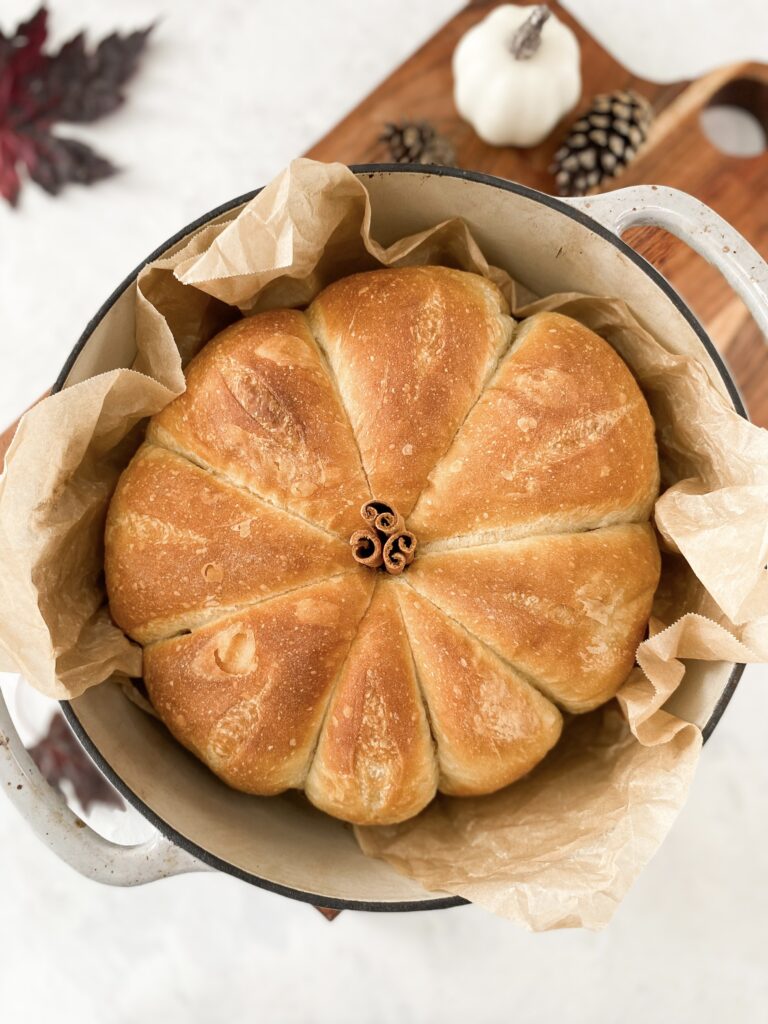 Pumpkin shaped bread in a dutch-oven with a cinnamon stick stem.