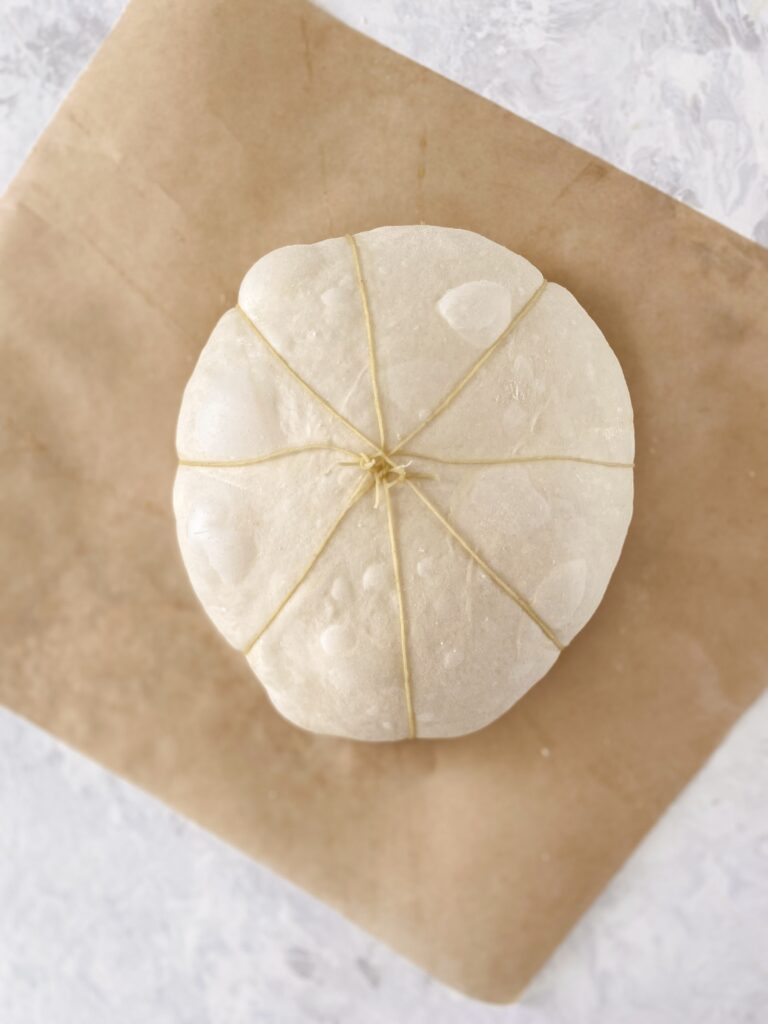 A round of dough wrapped in twine to make pumpkin-shaped bread.