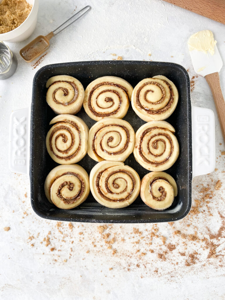 Unbaked cinnamon buns in a baking pan.