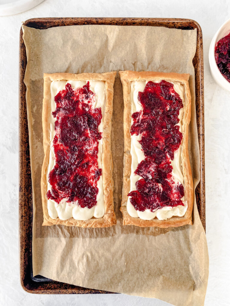 Puff pastry tarts filled with sweet cream cheese and cranberry jam ready to be baked into Cranberry Almond Danish.