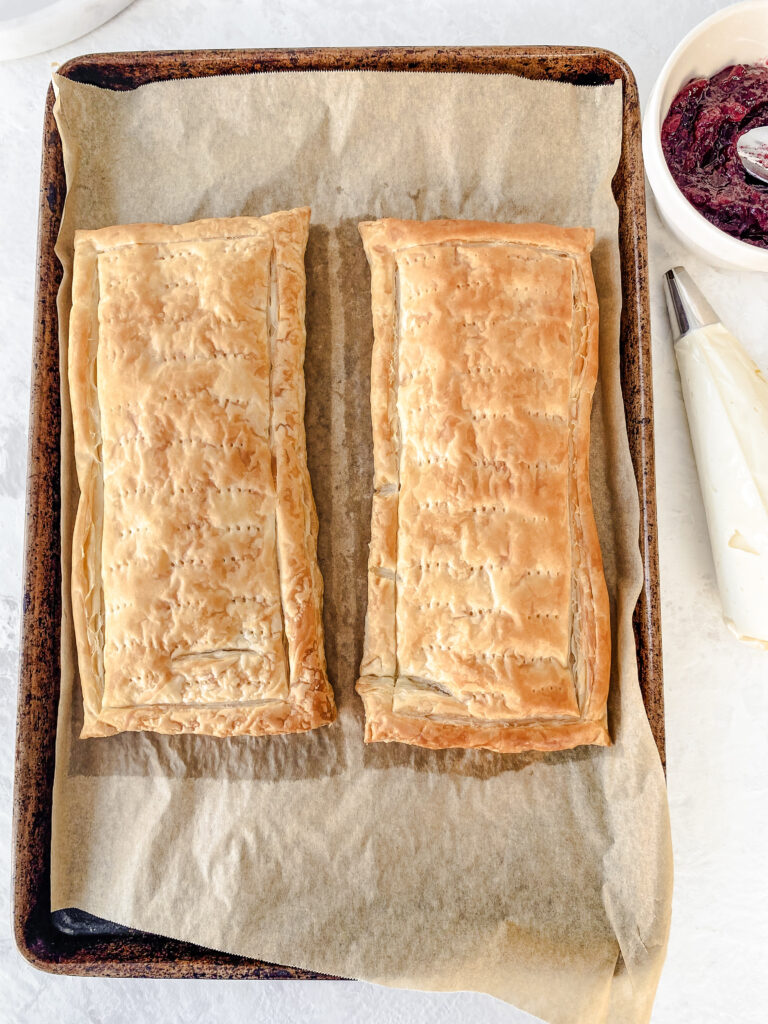 Two rectangles of baked puff pastry on a baking sheet.