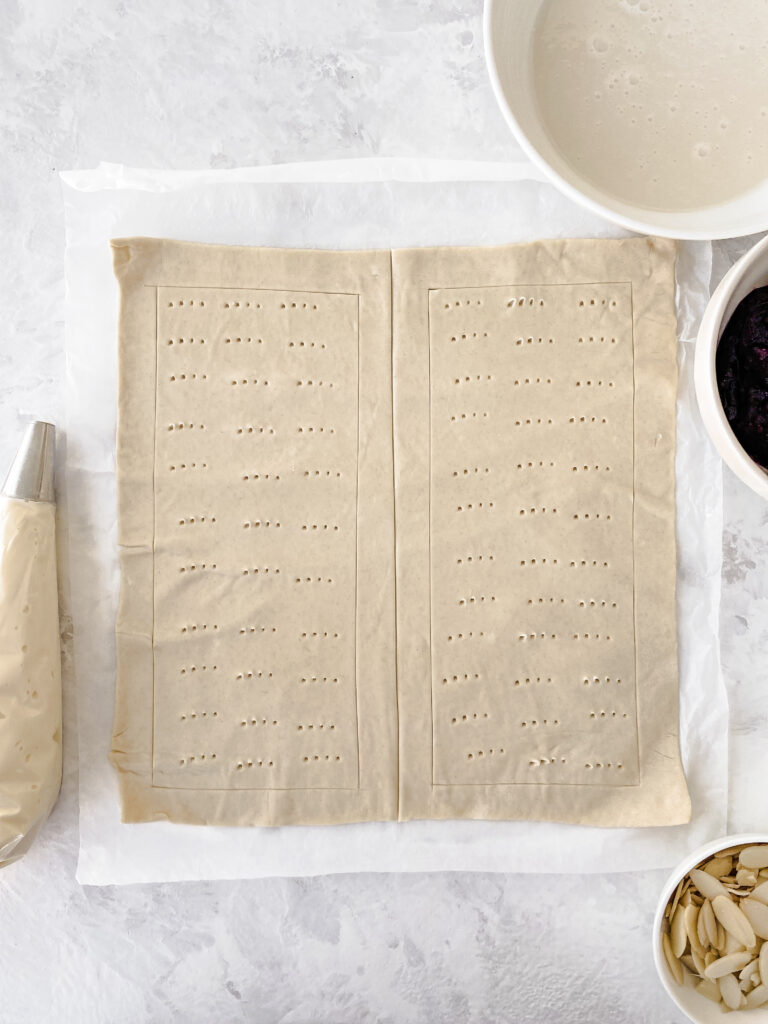 A sheet of puff pastry cut in half and docked to make two Danish pastries.