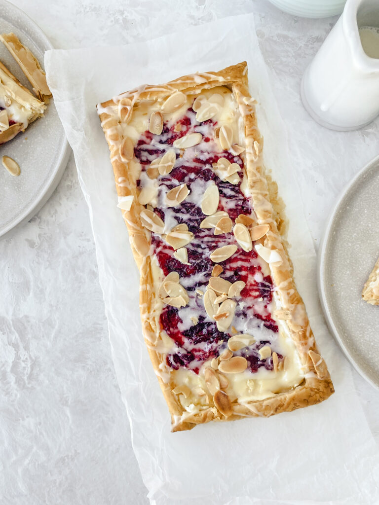 Shareable Cranberry Cream Cheese Danish topped with almond glaze and toasted almonds.