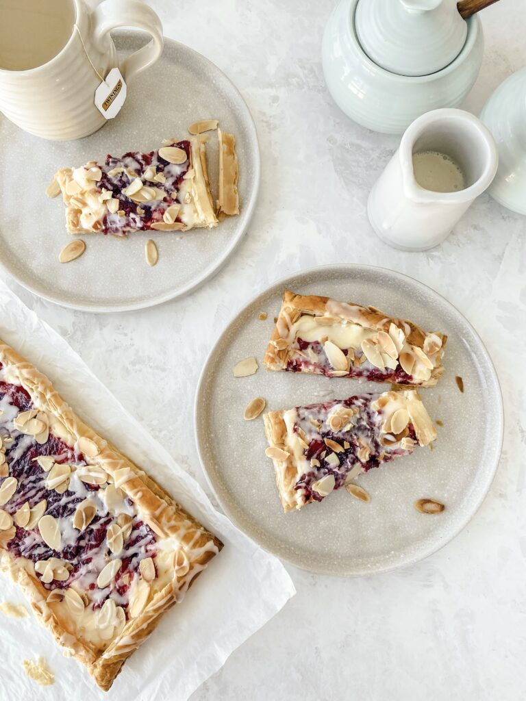 Cranberry Almond Danish slices served on two places alongside tea.