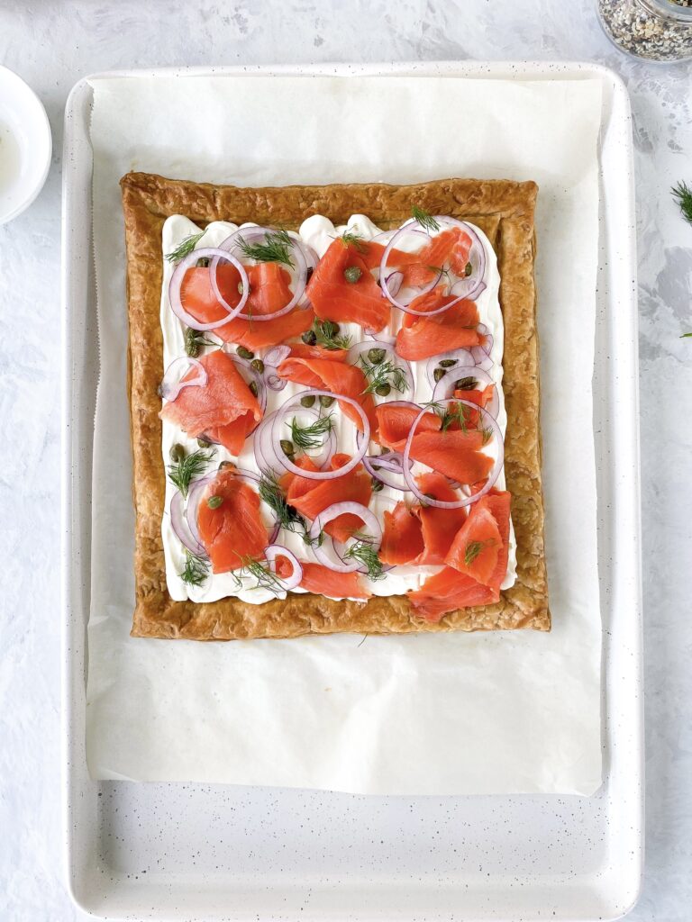 Puff pastry tart topped with whipped cream cheese and smoked salmon with capers, onions, and dill.