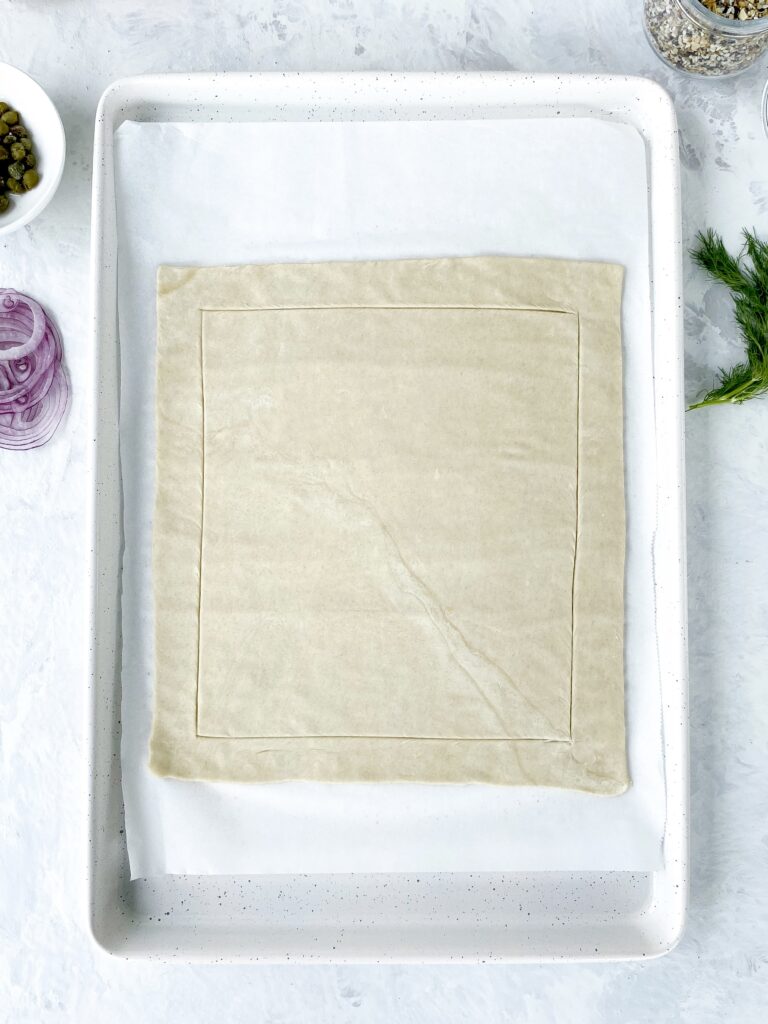 Unbaked puff pastry on a parchment-lined baking sheet.