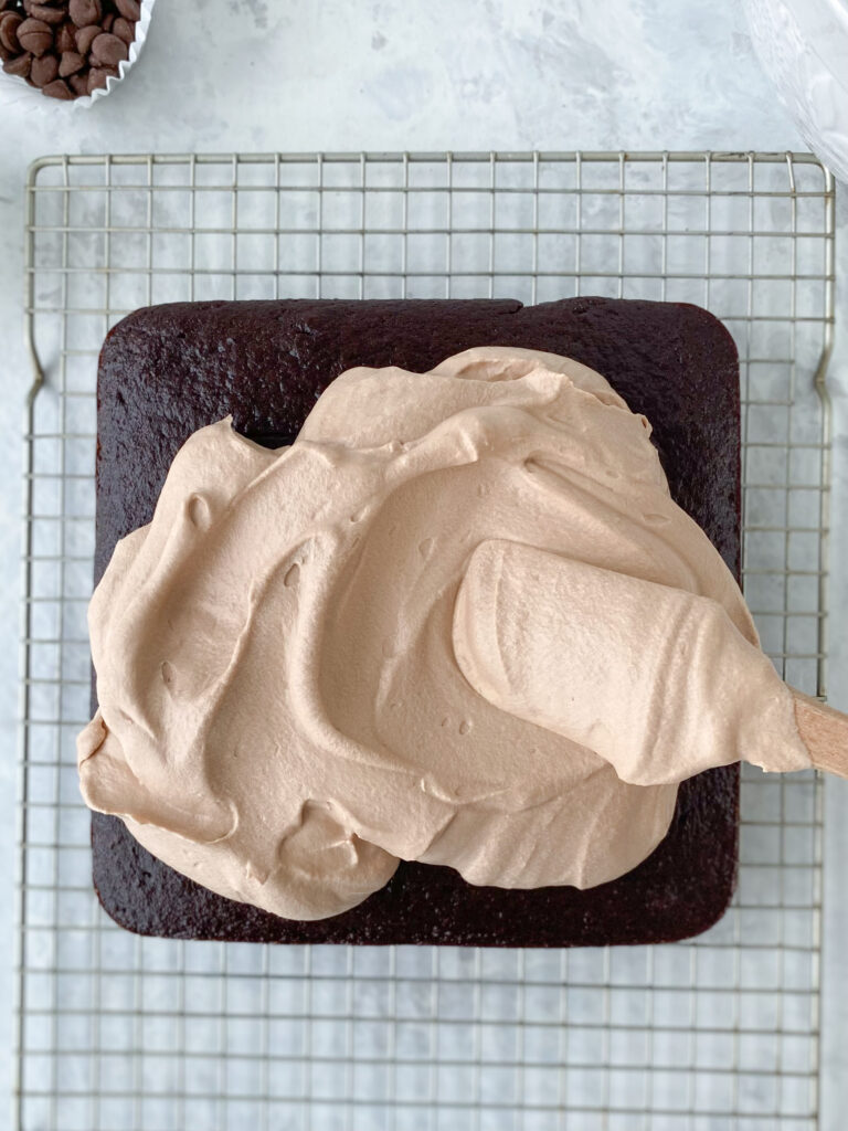 Chocolate mousse being spread over a chocolate cake.