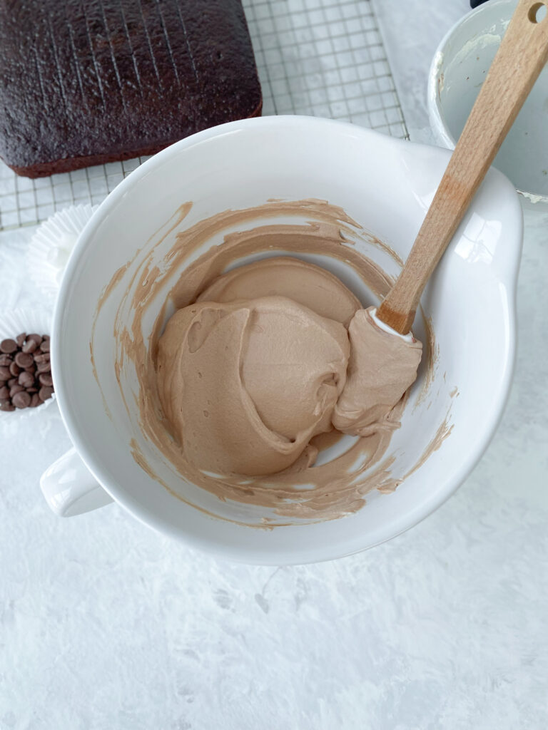 Chocolate mousse being folded together in a white bowl.