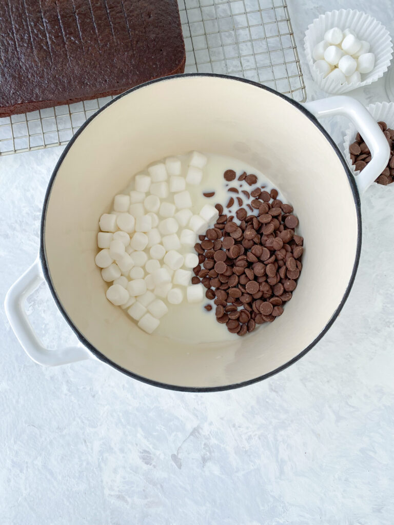 A cast-iron pot with mini-marshmallows, chocolate chips, and milk.