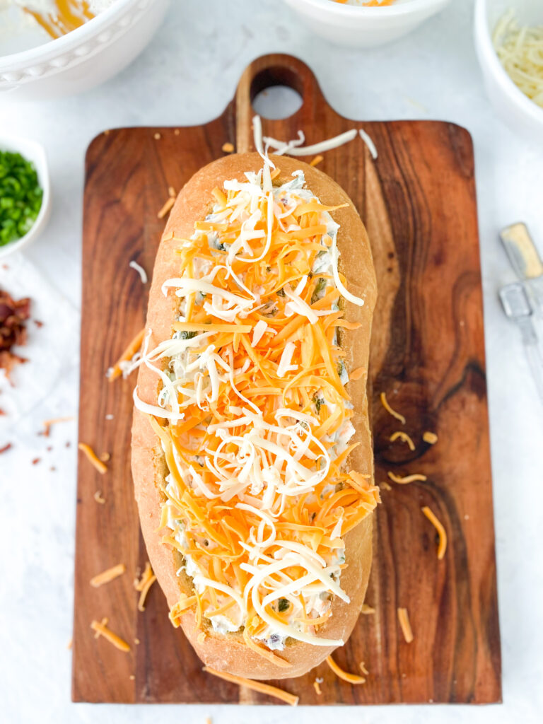 A French bread bowl stuffed with dip and topped with shredded cheese.