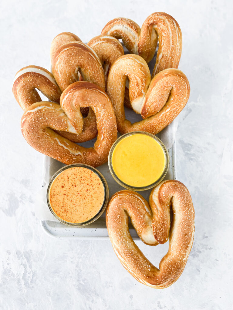 Heart shaped homemade soft pretzels with hot and honey mustard dips.