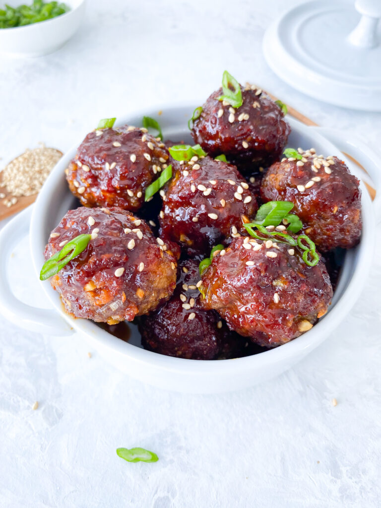 Sweet and spicy glazed gochujang meatballs topped with green onions and sesame seeds.