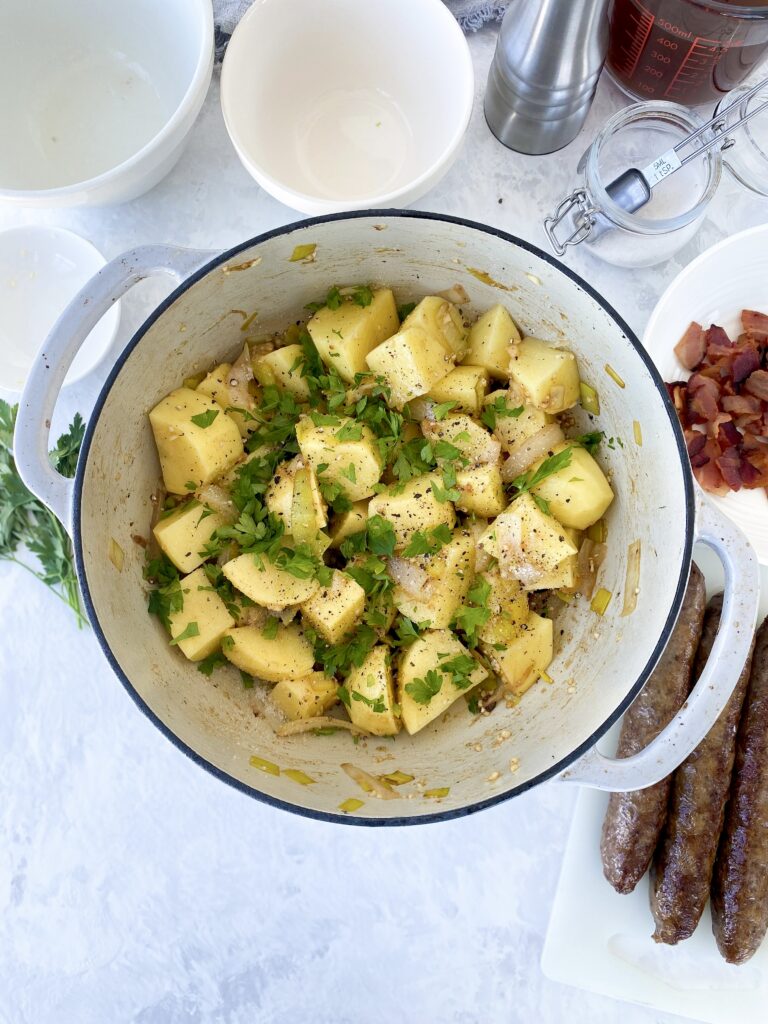 Yukon gold potatoes with softened onions, leeks, and parsley in a dutch oven.