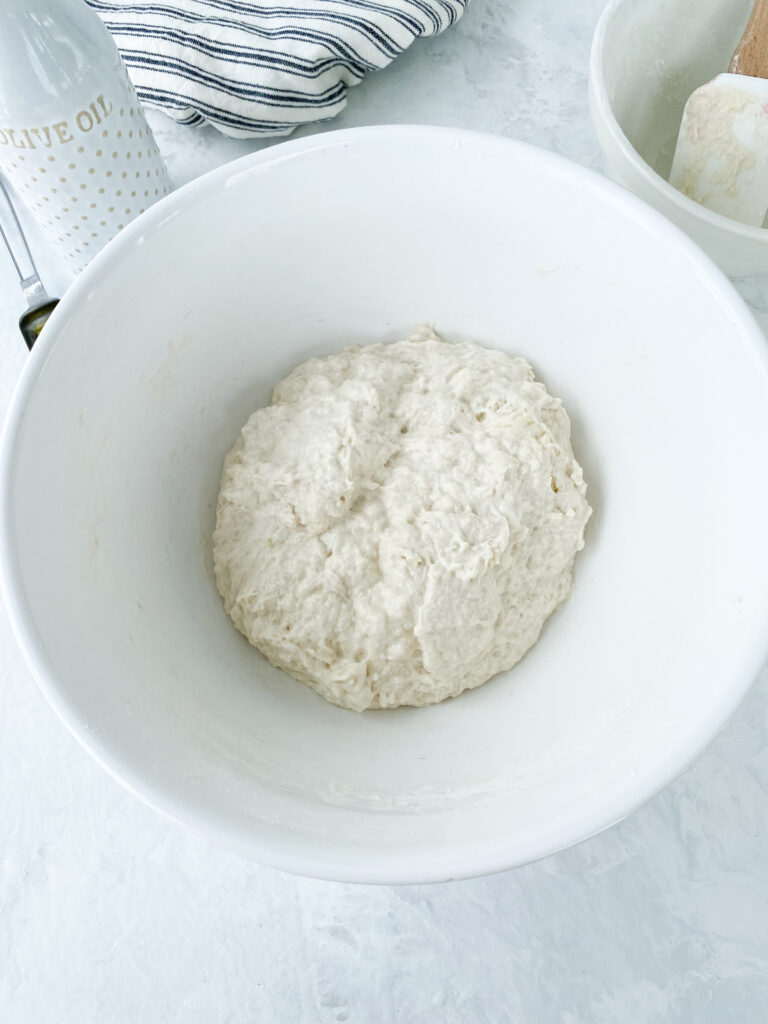 No knead focaccia dough resting in a white bowl.