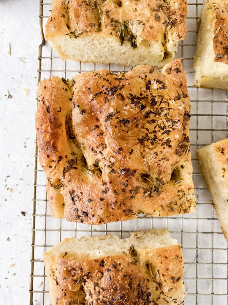 Focaccia bread sliced into squares on a wire rack.