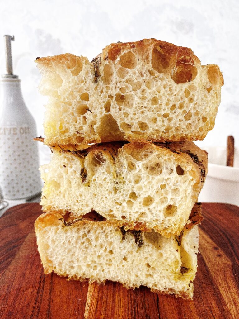 A stack of 3 squares of no knead focaccia bread with herb oil topping