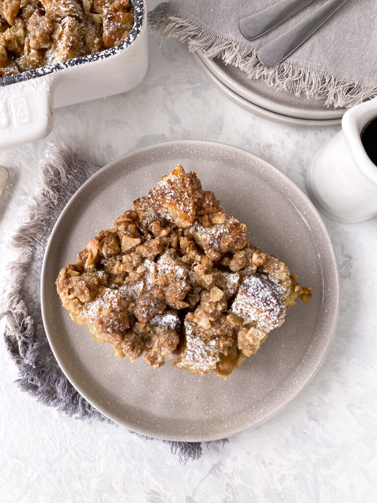 A slice of French toast casserole dusted with icing sugar.