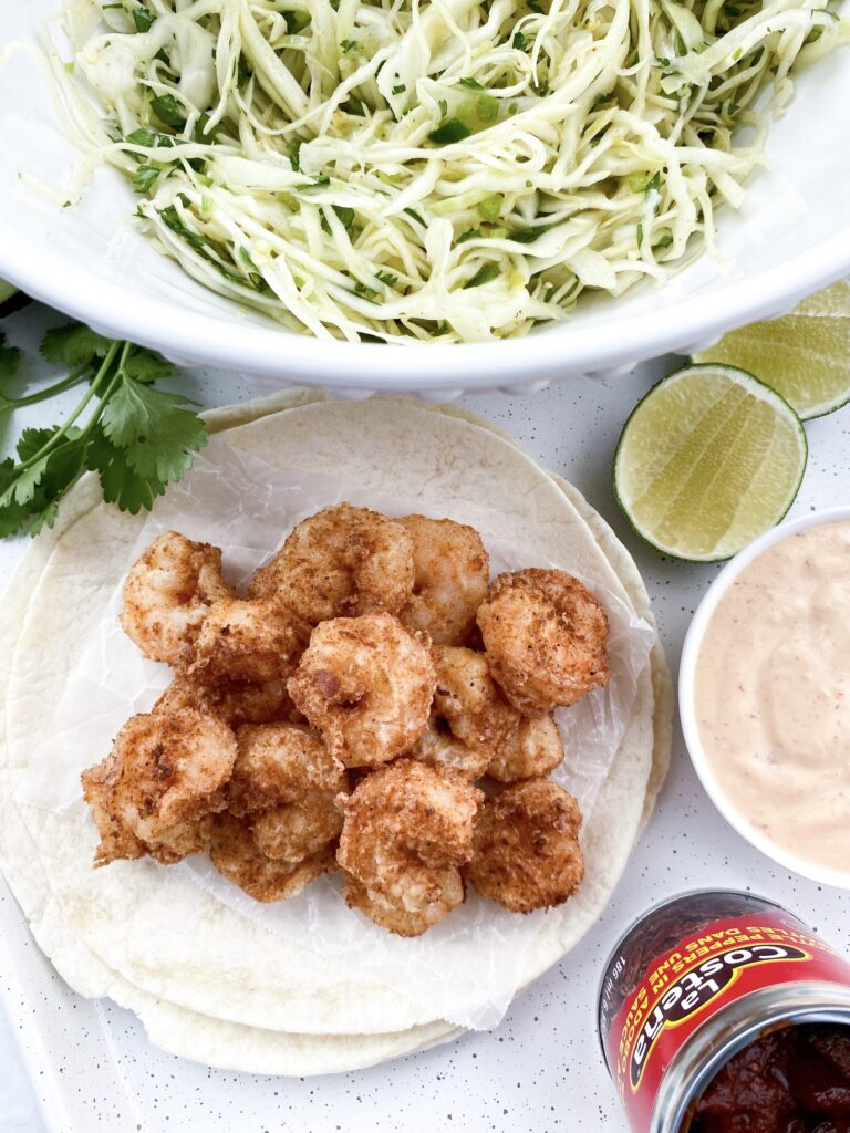 Baja shrimp tacos with crispy jumbo shrimp, crunchy cabbage slaw, thinly sliced red onions, and Baja sauce.