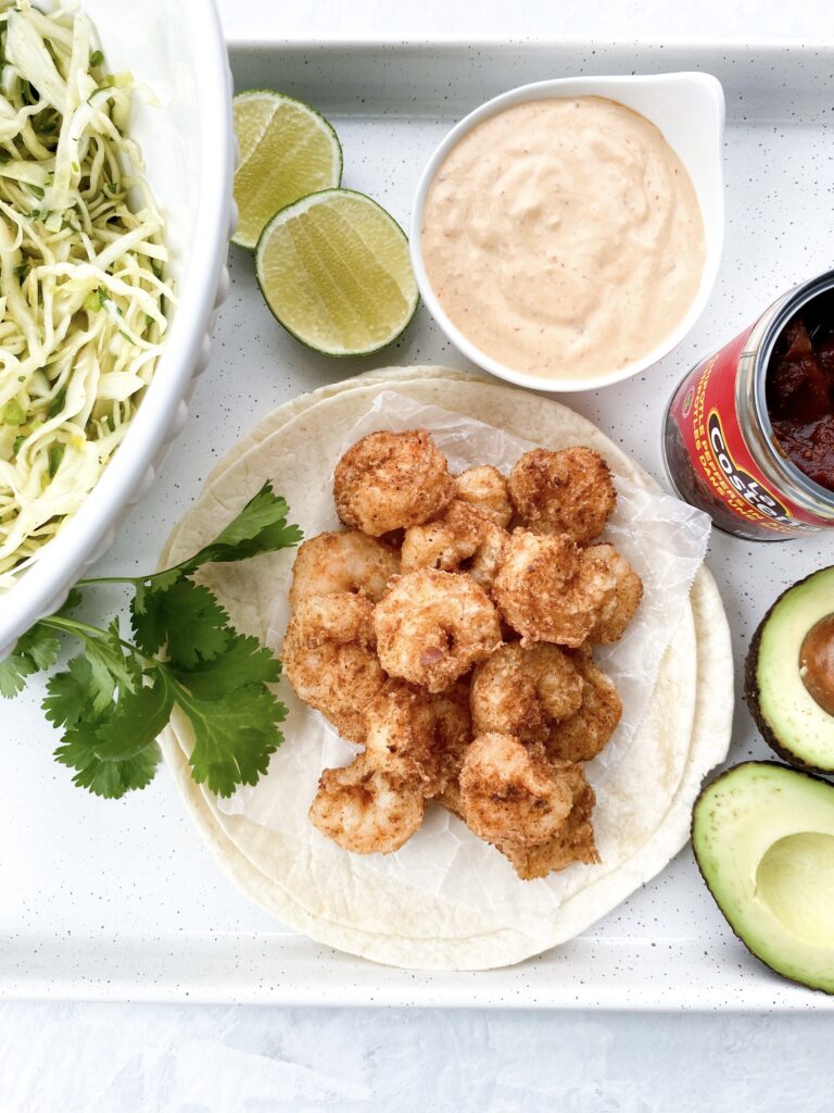 Baja-style shrimp tacos with crispy jumbo shrimp, crunchy cabbage slaw, thinly sliced red onions, and Baja sauce.
