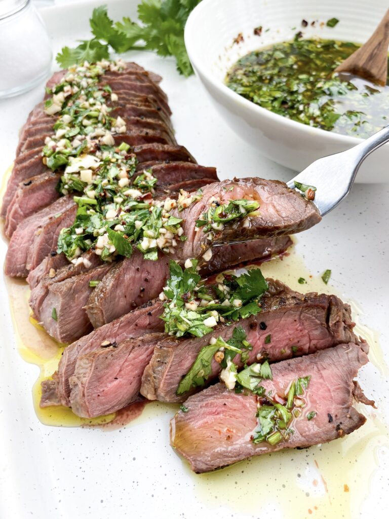 The ultimate summer steak perfectly cooked and topped with chimichurri sauce.