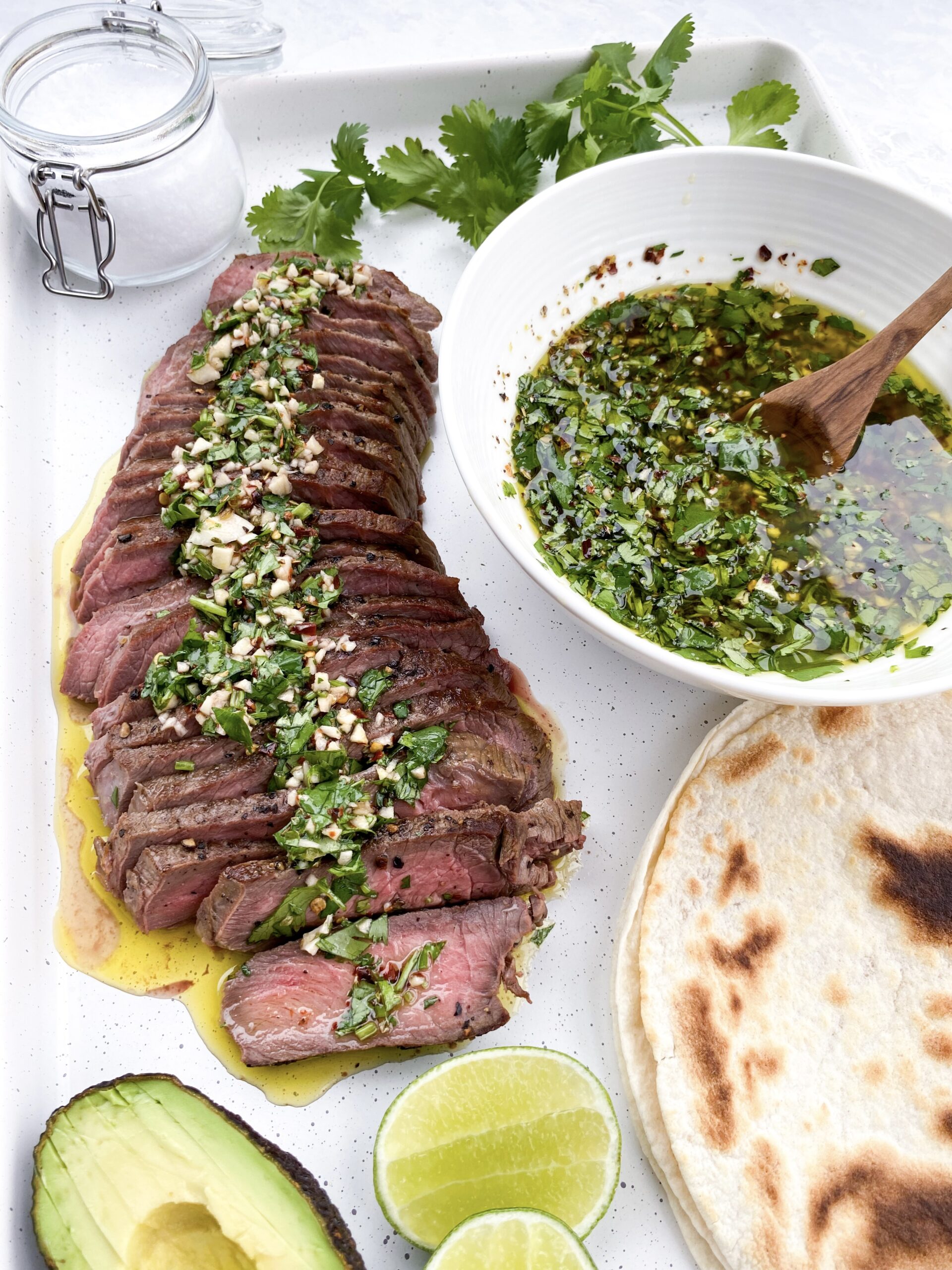 Spoon chimichurri sauce over sliced steak.