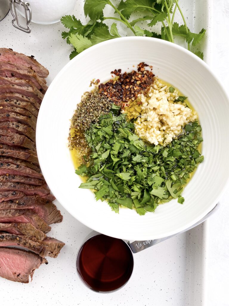 Ingredients for chimichurri sauce combined in a bowl.