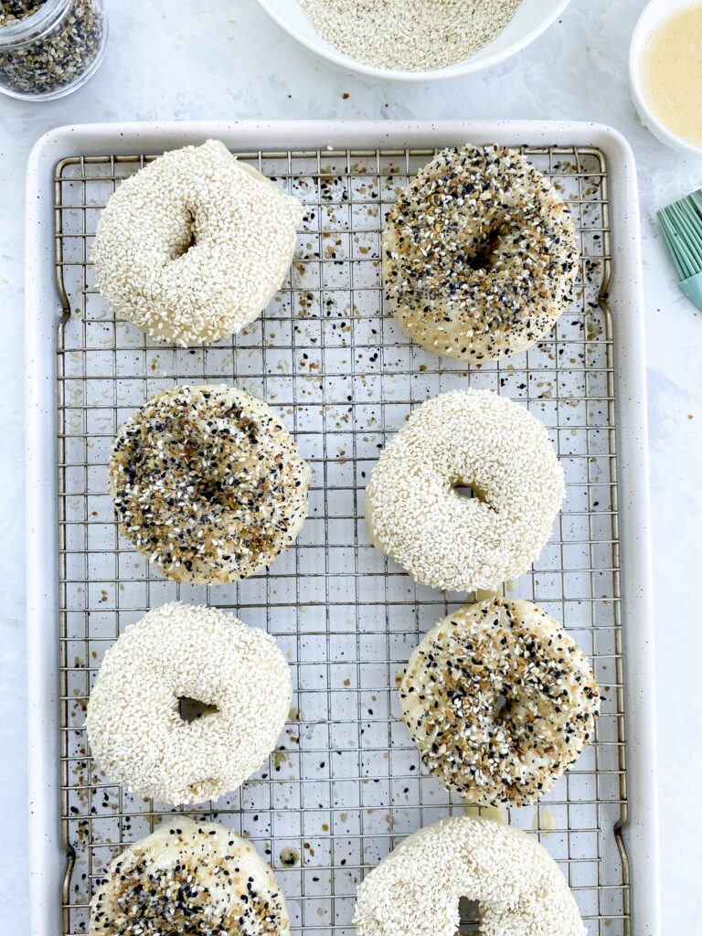 Bagels sprinkled with everything bagel seasoning and sesame seeds before baking.