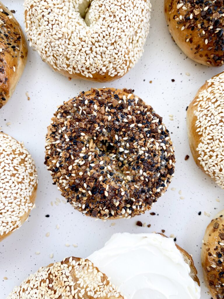 Bagels topped with everything bagel seasoning and sesame seeds with whipped cream cheese.