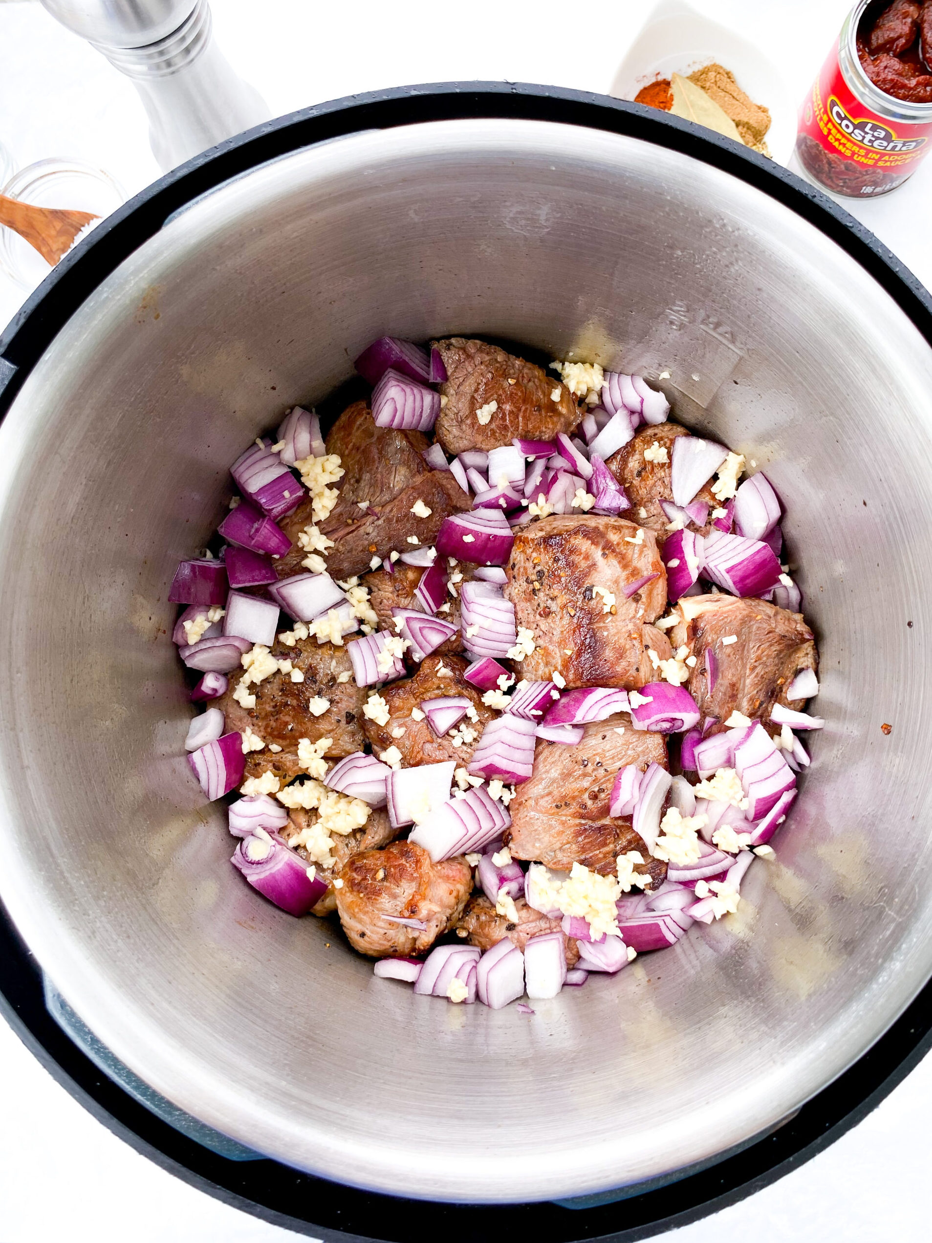 Browned beef cubes, onions, and garlic in an Instant Pot (slow cooker) for Mexican birria.