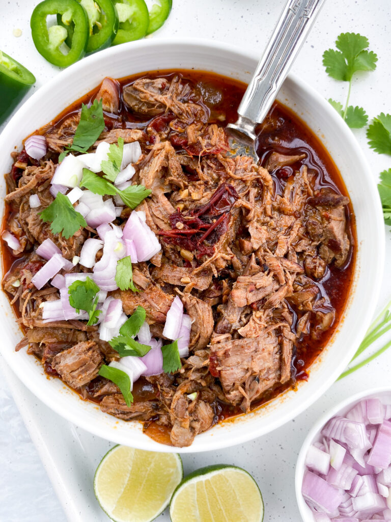Mexican beef birria in a bowl topped with diced onions and cilantro.