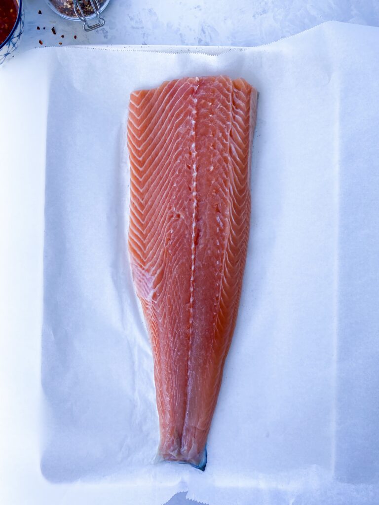 Side of salmon placed skin-side down on a parchment-lined baking sheet.