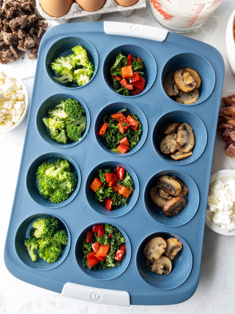 Assorted vegetables arranged in a 12-cup silicone muffin tin for homemade egg bites.