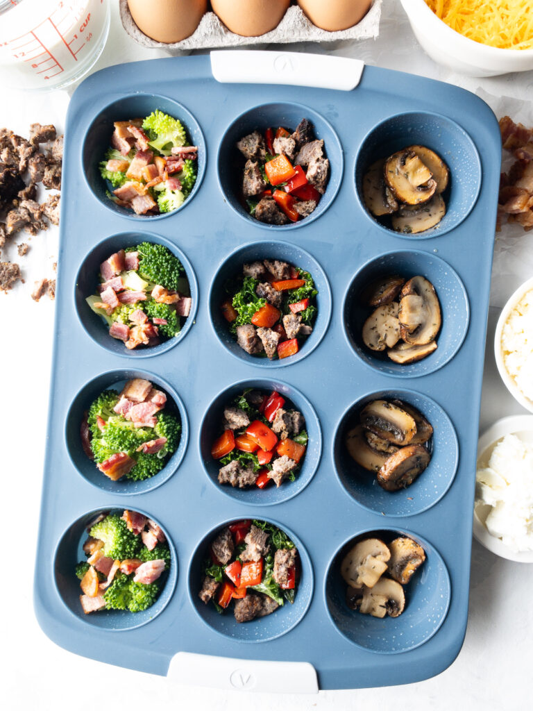 Assorted fillings arranged in a 12-cup silicone muffin tin for homemade egg bites.