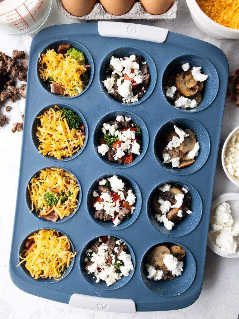Assorted fillings arranged in a 12-cup silicone muffin tin for homemade egg bites.