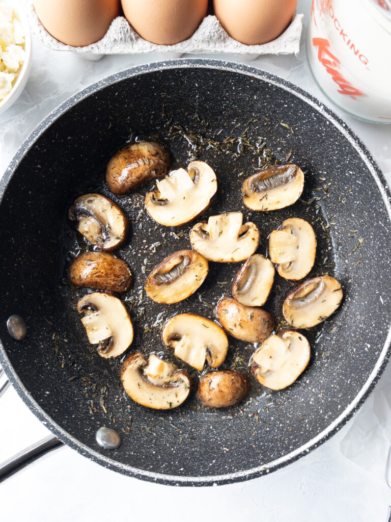 Sauteed mushrooms and thyme in a skillet.