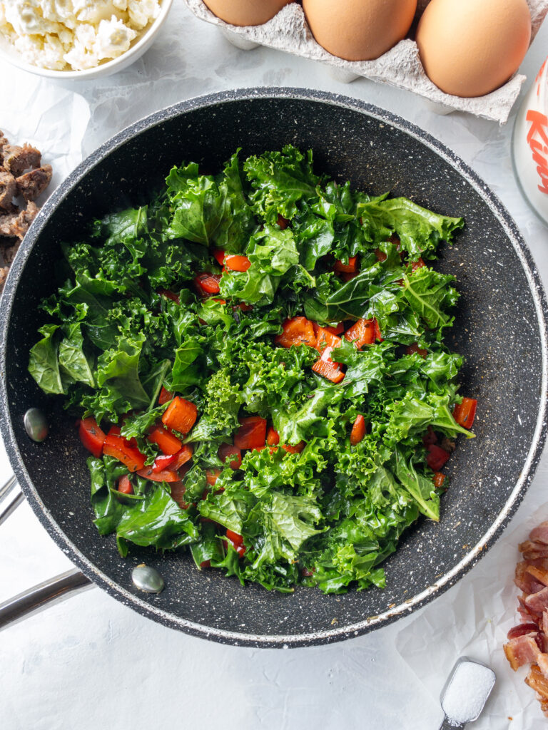 Sauteed kale and red bell pepper in a skillet.
