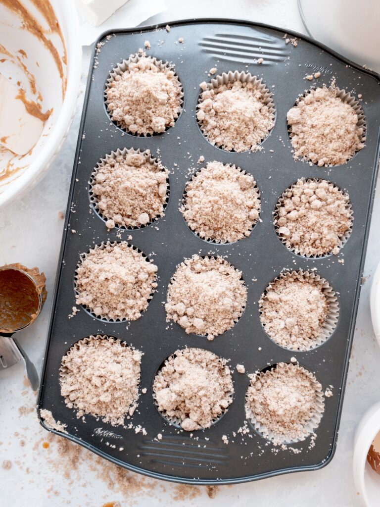 Simple pumpkin muffins sprinkled with cinnamon crumb topping before baking.