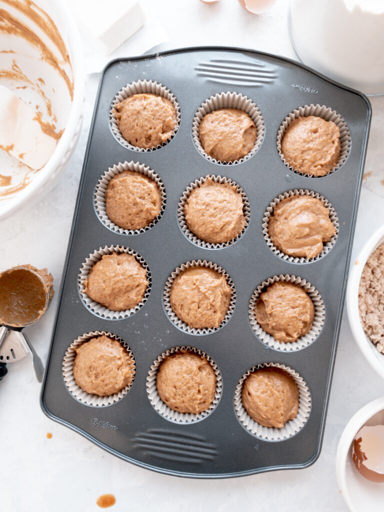 A standard muffin tray filled with pumpkin muffin batter.