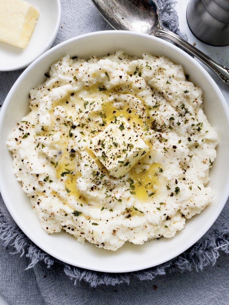 Creamy cauliflower mash topped with butter, cracked pepper, and parsley flakes.