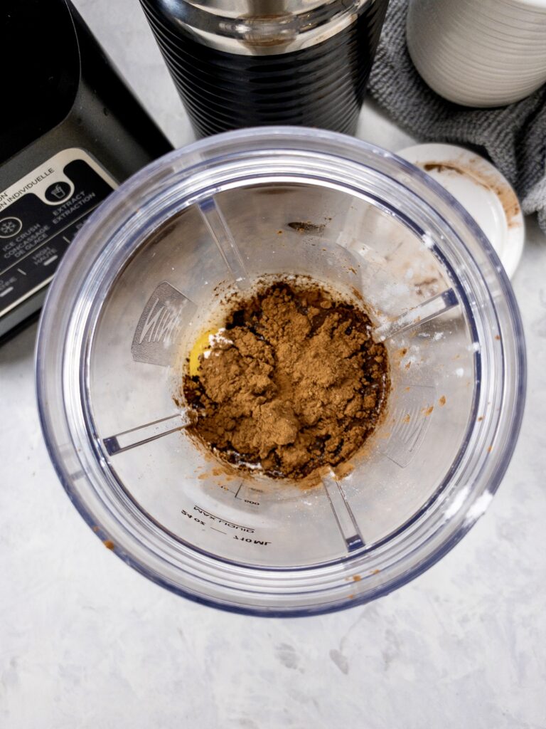 Add almond milk, cocoa powder, powdered sweetener, ghee, MCT oil, and vanilla to a blender.